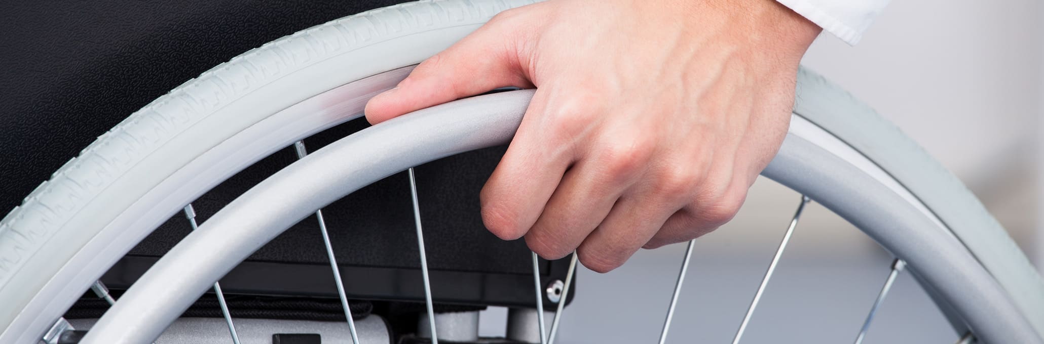 Main sur une roue de fauteuil roulant